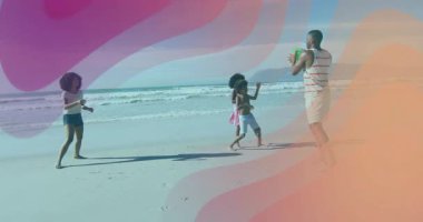 Aile kumlu sahilde plaj topu oynuyor. Pembe-mor dalgalar sağlığa katkıda bulunuyor. Tatil, açık hava, boş zaman, aktivite, oyun alanı, tasasız, güneş ışığı