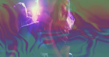 Takım müzik stüdyosunda işbirliği yapıyor, kulaklık takıyor ve monitörden neon çarpıtmaları izliyor. Neon, multimedya, canlı, işbirlikçi, fütürist, soyut, dalgın