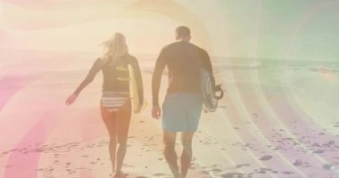 Sörf tahtası taşıyan sörf tahtası taşıyan çift hareket eden pastel mercekli plajlar seyahat reklamını yükseltiyor. Sahil, okyanus, kıyı şeridi, aktif, açık hava, güneşli, boş zaman