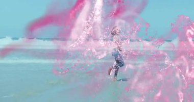 Yaratıcı pazarlama konsepti için sahil şeridi boyunca dönen pembe tozlu bir kadın. Macera, canlılık, canlı, açık hava, dinamik, enerjik, yaşam tarzı