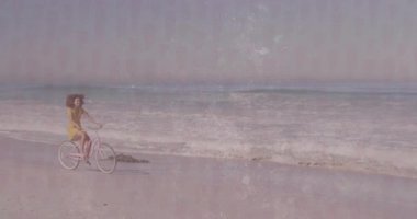 Sahil şeridi boyunca pembe kruvazör bisikleti süren bir kadın. Yüzen sağlık ikonu sergiliyor. Canlı, kaygısız, açık hava, boş zaman, doğa, gençlik, dinginlik