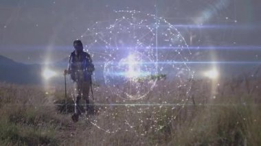 Yürüyüşçü şafakta dağ yolunda yürüyor, parlayan dijital ağ küresi teknolojisi sergiliyor. Macera, keşif, bağlantı, yenilik, açık hava, teknoloji, manzara