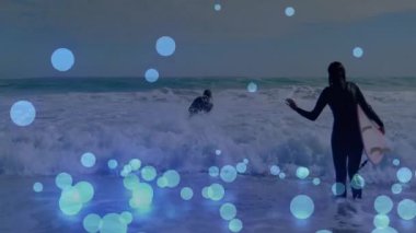 İki sörfçü köpüklü okyanus dalgalarında yüzüyor ve mavi daireler kullanarak teknolojilerini sergiliyor. Macera, sahil, eğlence, dinamik, su, canlı, eğlence