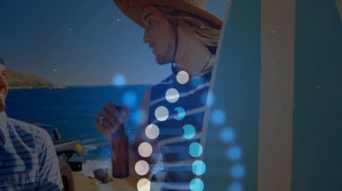 İki adam okyanus kenarında sörf tahtası tutuyor, gülümsüyor ve teknolojiyi parlayan daireler ve çubuklar gösteriyor. Arkadaşlar, plaj, tatil, eğlence, dijital, modern, yaşam tarzı