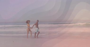 Pazarlama reklamında, canlı dalga grafikleri ve pusula ikonlarıyla kıyı boyunca yalınayak yürüyen çift. Romantizm, macera, sükunet, günbatımı, boş zaman, manzara, uyum.