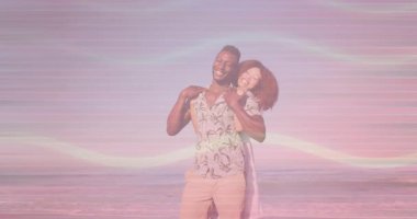 Kadın, gün batımında kumlu sahilde adama arkadan sarılıyor. Canlı kalp ikonlarıyla seyahat ediyor. Romantizm, mahremiyet, boş zaman, açık hava, dinginlik, coşku, bağlantı