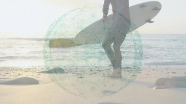 Plajda sörf tahtası inceleyen dalgıç kıyafeti giymiş bir adam. Teknoloji eğilimlerini gösteren bir deniz mavisi ağ örtüsü var. Macera, sahil şeridi, dinginlik, keşif, teknoloji, bağlantı, açık hava