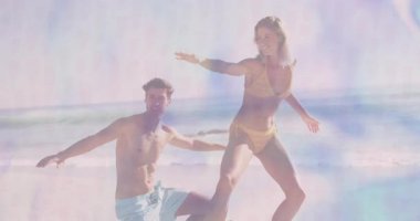 Yüzen kalp ikonları ve pazarlama grafikleriyle sığ sahil sularında dans eden ve sıçrayan çiftler. Romantizm, eğlence, sükunet, pastel, kaygısız, uyum, rahatlama