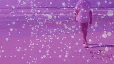 Hasır şapkalı bir adam kumlu sahilde okyanusa bakıyor ve teknoloji ağı örtüsü sergiliyor. Yalnızlık, rahatlama, sükunet, açık hava, doğa, bağlantı, rahatlık.