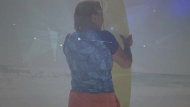 Kumlu kumsalda elinde sörf tahtası olan son sınıf öğrencisi bir kadın. Animasyon teknolojisiyle yanıp sönüyor. Kıyı şeridi, macera, canlılık, dijital sanat, boş zaman, açık hava, canlı