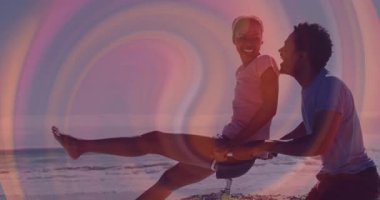 Kadın sarı bisiklete binerken, erkek gün batımında kumlu sahilde bisikleti itiyor, sağlık simgeleri gösteriyor. Romantik, boş zaman, açık hava, canlı, neşeli, uyum, macera