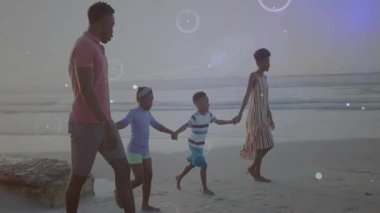 Ailenin kıyı boyunca el ele yürümesi, teknoloji tasarımı için dijital ağ örtüsü sergilemesi. Aileler, yaşam tarzı, minimalizm, bağlantı, dinginlik, teknoloji, açık hava