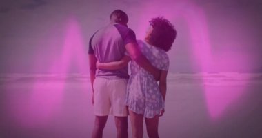 Kıyı şeridinde duran erkek ve kadın dijital pazarlama kampanyası için pembe kaplama tasarlıyorlar. Romantizm, çift, deniz kenarı, dinginlik, çiçekli, sıradan, yaşam tarzı