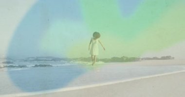 Kadın kumlu sahilde çıplak ayakla yürüyor. Refah pazarlaması için pastel ışık sızıntısı var. Dinginlik, sükunet, bohem, doğalcılık, sahil, huzur, huzur