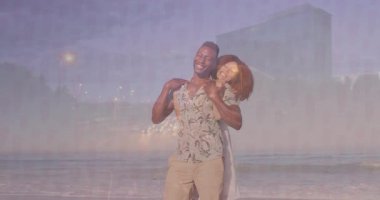 Gün batımında kumsalda kucaklaşan bir çift. Kalp ikonu havada süzülüyor ve sağlık grafiği çiziyor. Romantizm, samimiyet, rahatlama, sahil, huzur, neşe, şefkat