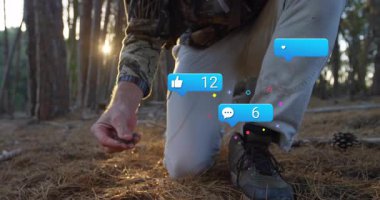 Çam ormanında diz çökmüş bir adam, okun yayını inceliyor, spor teknisyenleri üst üste biniyor. Doğa, açık hava, kesinlik, macera, vahşi yaşam, vahşi doğa, avlanma.