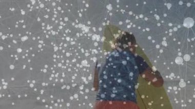 Kıyı şeridindeki kırmızı sörf tahtasında diz çökmüş bir kadın teknoloji için dijital ağ örtüsü sergiliyor. Denizcilik, sağlık, bağlantı, macera, canlı, yaşam tarzı, açık hava