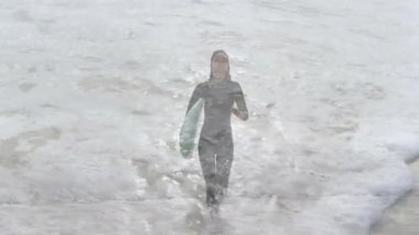 Sörften sahile yürüyen kadın spor dalgasındaki animasyon dalga yüksekliği grafiklerini ve ölçümlerini gösteriyor. Macera, aktif giyim, dinamik, kıyı, açık hava, spor, enerji