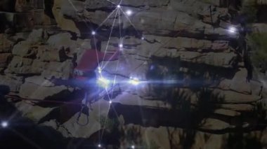 Kanyon duvarları arasında ip üzerinde dengede duran bir adam, teknolojiyi birbirine bağlayan parlak ağ hatlarını gösteriyor. Macera, dayanıklılık, modern, keşif, canlı, doğa, dayanıklılık.