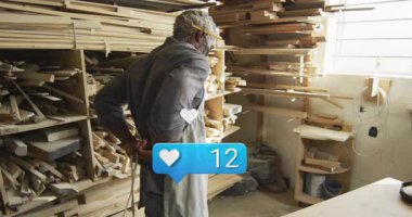 Ahşap atölyesinde duran bir adam canlandırılmış kalplerle ahşap kalaslar sergiliyor ve tezgah gibi mavi. Zanaatkar, marangozluk, atölye, kereste, kereste, aletler, iç mekan