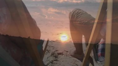 Gün batımında plaj sandalyelerinde el ele tutuşan bir çift. Animasyon sağlık ikonu ve parlayan güneş ışınlarıyla. Romantizm, samimiyet, rahatlama, manzara, huzur, rahatlık, uyum.