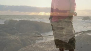 Son sınıf öğrencisi gün batımında kayalık kıyı şeridinde duruyor ve finans için yüzen haritalarla harmanlıyor. Kıyı, sükunet, tefekkür, manzara, dramatik, doğal, ilham verici.