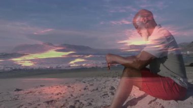 Adamın biri kumlu günbatımı plajında meditasyon yapıyor. Canlandırılmış kalp ikonu ve sağlık tablosuyla. Dinginlik, rahatlama, sağIık, farkındalık, manzara, doğa, canlılık