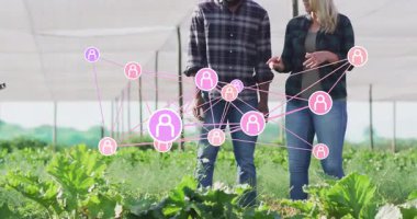Gölge evde yürüyen iki çiftlik ortağı yüzen ağ simgeleriyle yapraklı ürünleri inceliyor. Tarım, işbirliği, yenilik, tarım, sürdürülebilirlik, teknoloji, bahçıvanlık