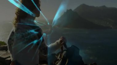 Uçurumun kenarında duran ve teknolojiyle temalı veri grafikleri olan bir kadın. Macera, keşif, vahşi doğa, manzara, motivasyon, ufuk, seyahat