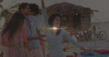 Gün batımında plaj pikniği masasında grup dansı, fener ikonları ve pazarlama grafikleri gösteriliyor. Şenlikli, açık hava, kutlama, coşku, eğlence, sosyal, sıcak
