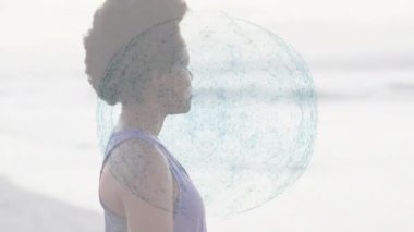 Kadın plajda meditasyon pozisyonunda duruyor ve animasyon teknolojisi ağı veri akışını gösteriyor. Sağlık, huzur, farkındalık, teknoloji, fütürizm, açık hava, sükunet