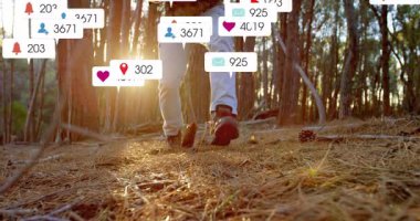 Sosyal medya simgeleri havada süzülürken içerik yaratıcısı çam ormanında diz çökme teçhizatı ayarlıyor. Macera, açık hava, keşif, doğa, vahşi doğa, engebeli yaşam tarzı.