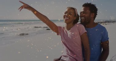 Çiftler kumlu sahil şeridinde okyanusu işaret ediyor. Parıltı, seyahat pazarlamasını ön plana çıkarıyor. Romantizm, boş zaman, sahil, neşeli, canlı, açık hava, arkadaşlık.