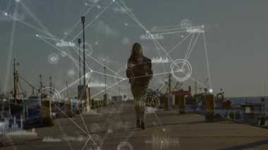 Gün batımında yürüyen kadın, ağ hatları, düğümler ve bar çizelgeleri teknoloji verilerini gösteriyor. Liman, denizcilik, sanayi, ulaşım, keşif, yenilik