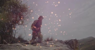 Erkek yürüyüşçü yıldızımsı ışıkların altında kayalık yamaçlara tırmanıyor ve sağlık verilerini gösteriyor. Macera, keşif, engebeli, açık hava, manzara, dayanıklılık, vahşi doğa.