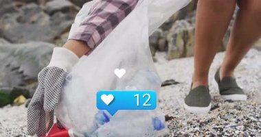 Kayalık kıyı şeridinde çöp toplayan bir kadın, kalp ikonlarıyla pazarlama reklamı gösteriyor ve tezgah gibi. Çevre, çevre, koruma, aktivizm, açık hava, yoldaşlık, dijital