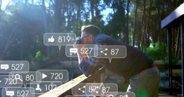 Erkek fotoğrafçı pazarlama için ormanı kamerayla yakalıyor. Yüzen kalpler ve çanlar gösteriyor. Doğa, manzara, açık hava, keşif, macera, sükunet, vahşi doğa.