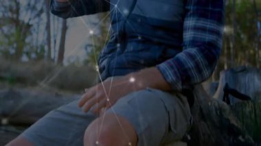 Metal bardaktan içen adam, ağ teknolojisi hatlarını ve düğümleri sergiliyor. Çevre dostu, vahşi doğa, bağlantı, doğa, keşif, minimalizm, macera