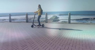 Sahil yolu boyunca scooter süren kadın yüzen grafiklerle pazarlama kampanyası verilerini gösteriyor. Sağlıklı yaşam tarzı, açık hava aktivitesi, şehir manzarası, şehir eğlencesi, fitness, macera, boş zaman