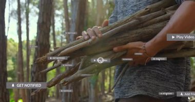 Çam ormanında tahta çubuklar tutan bir adam, yüzen AR teknolojisi bildirim simgelerini sunuyor. Doğa, macera, teknoloji, fütürizm, vahşi doğa, açık hava, yenilik