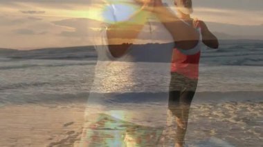 Yoga partnerleri gün batımında plajda meditasyon yapıyorlar. Canlandırılmış sağlık simgeleri ve dalga grafikleriyle. Dinginlik, farkındalık, sağlık, doğa, sükunet, yansıma, bağlılık.