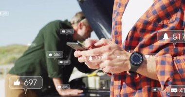 İki meslektaş, akıllı telefonlarıyla yol kenarını inceliyor. Pazarlama için sosyal simgeler gösteriyorlar. Otomotiv, teknoloji, bakım, işbirliği, açık hava, dijital, mekanik