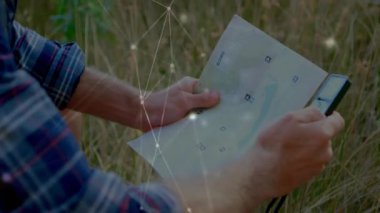 Dışarıdaki alanın üzerinde katlanmış haritayı tutan adam, teknoloji için parlayan ağ düğümlerini ve çizgileri gösteriyor. Klasik, rustik, organik, macera, bağlantı, keşif, teknoloji