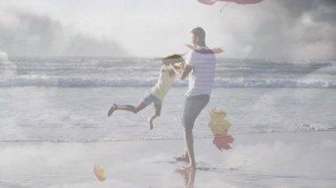 Baba, kızını sahilde sallıyor ve yüzen sonbahar yapraklarıyla pazarlama konseptini gösteriyor. Aile, açık hava, huzur, dostluk, kutlama, köy eğlencesi.