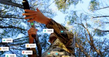 Erkek avcı ormanda yay çizerek pazarlama için yüzen sosyal medya simgeleri gösteriyor. Macera, vahşi doğa, açık hava, gerçekçilik, modern, vahşi yaşam, kesinlik.