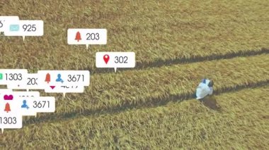 Adam yeşil alanda diz çöküp tarım pazarlaması için yüzen sosyal medya ikonlarıyla toprağı teftiş ediyor. Tarım sektörü, kırsal kesim, dijital katılım, çevre, tarım, teknoloji, tanıtım