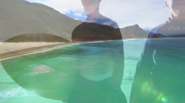 İki sörfçü sahilde göğsüne kadar suya batmış sörf tahtaları ve sağlık dalgaları çizelgesi gösteriyor. Macera, yaşam tarzı, coşku, eğlence, keşif, sahil, açık hava