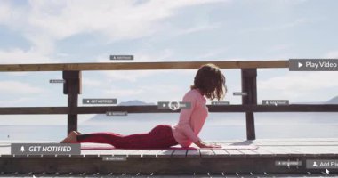 Göl kenarındaki güvertede kobra yoga pozu veren kadın sağlık teknolojisinde UI grafikleri sunuyor. Doğa, sağlık, rahatlama, teknoloji, dinginlik, farkındalık, açık hava