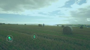 Yüzen rüzgar türbini, yenilenebilir enerji için saman balyalarının üzerindeki ikonları geri dönüşümlü olarak gösteriyor. Tarım arazisi, sürdürülebilirlik, eko-bilinçli, yenilenebilir, tarım, çevre, enerji