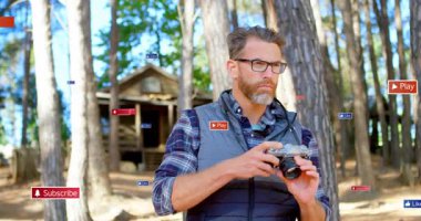 Sosyal medya aboneliğiyle ormanda kamerayı elinde tutan adam etrafta yüzen ikonlar gibi oynuyor. Doğa, açık hava, macera, yürüyüş, köy, sükunet, keşif